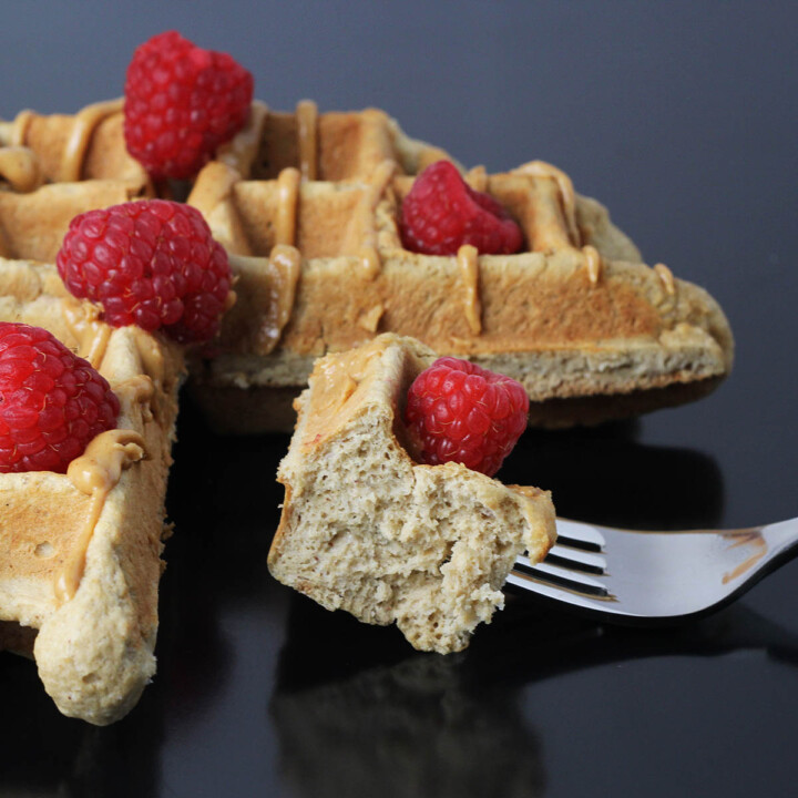 three quarters of a peanut butter belgian waffle topped with raspberries